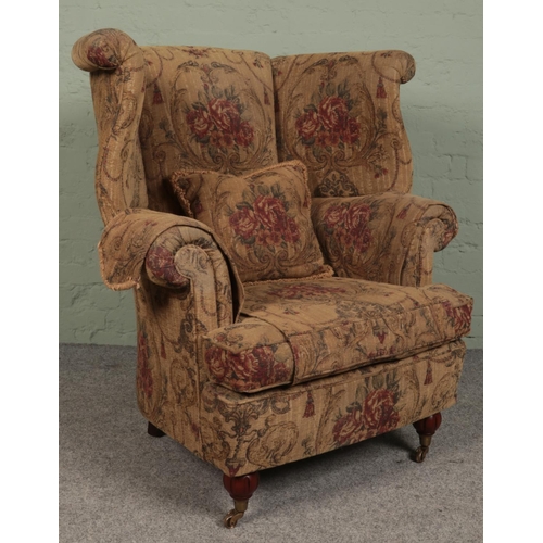 412 - A large wingback upholstered armchair. (115cm x 97cm)