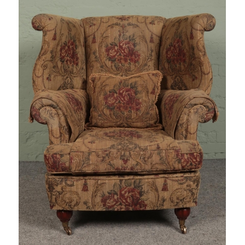 412 - A large wingback upholstered armchair. (115cm x 97cm)