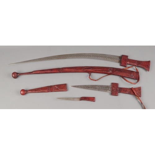 379 - An early 20th century tribal sword having a clad tooled leather handle of traditional form, steel cu... 