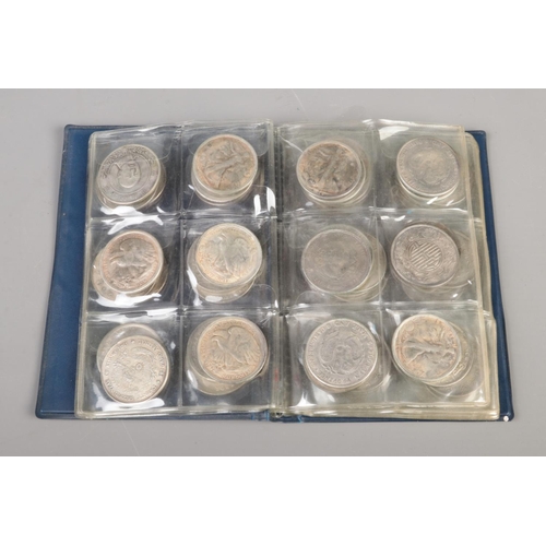 80 - A folder of white metal reproduction world coins including China, India and the US along with small ... 