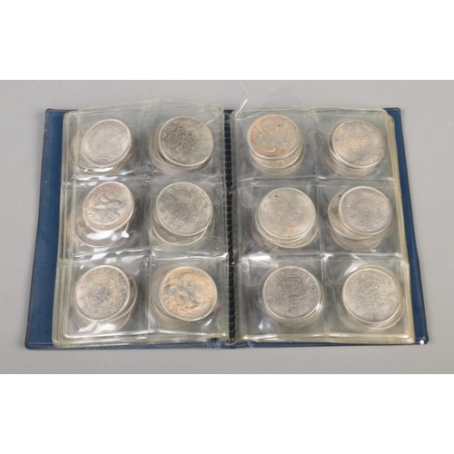 80 - A folder of white metal reproduction world coins including China, India and the US along with small ... 