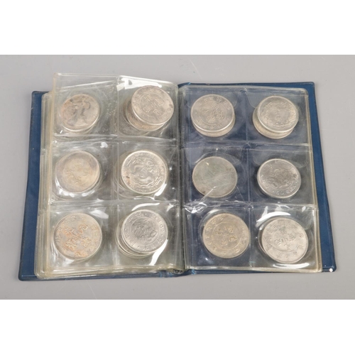 80 - A folder of white metal reproduction world coins including China, India and the US along with small ... 