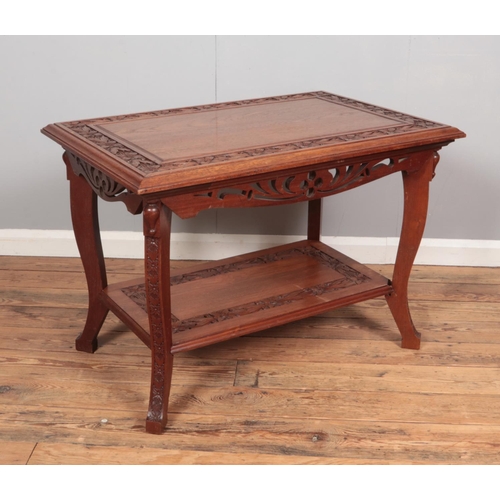 385 - A carved oak two tier side table with floral decoration. (65cm x 92cm x 62cm)