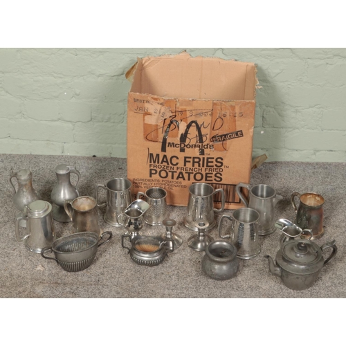 187 - A box of metalwares. Includes teapot, ewers, tankards, twin handle bowls, etc.