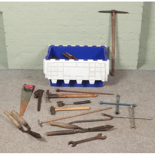 189 - A box of tools. Includes pickaxe, axes, hammers, shears, etc.