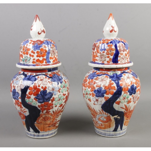 50 - A pair of Chinese lidded vases, decorated with Prunus blossom in blues and oranges, with pointed fin... 