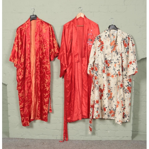 267 - Three Japanese silk kimonos. Two red and one cream with floral design.