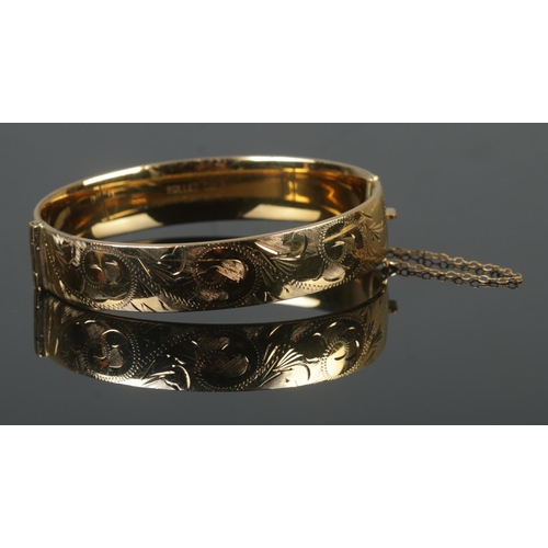 379 - A hinged rolled gold bangle, with '10 Years Guaranteed' inscribed to inside of band.