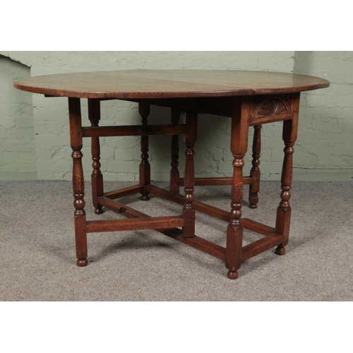 468 - An oak drop leaf gate leg table featuring carved sun burst motif to ends. Approx. dimensions with le... 