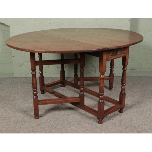 468 - An oak drop leaf gate leg table featuring carved sun burst motif to ends. Approx. dimensions with le... 