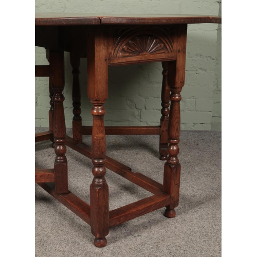 468 - An oak drop leaf gate leg table featuring carved sun burst motif to ends. Approx. dimensions with le... 