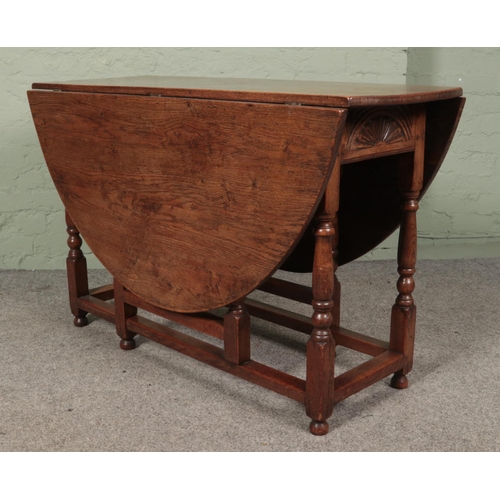 468 - An oak drop leaf gate leg table featuring carved sun burst motif to ends. Approx. dimensions with le... 