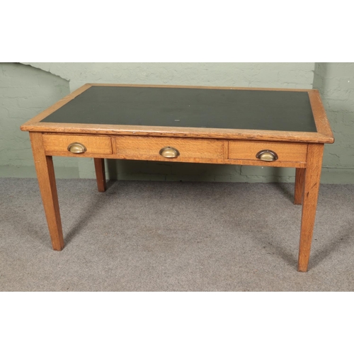 490 - A large leather top oak writing desk with three drawers and brass cup handles. 

Hx77cm
Wx153cm
Dx92... 