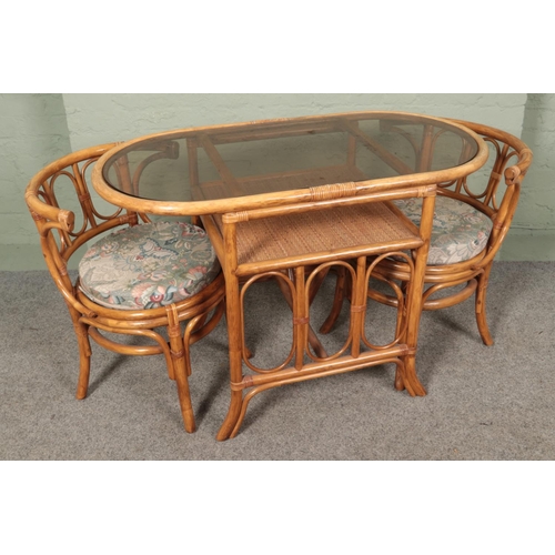 491 - A glass top conservatory table and two chairs. Approx. table size 110cm x 56cm.