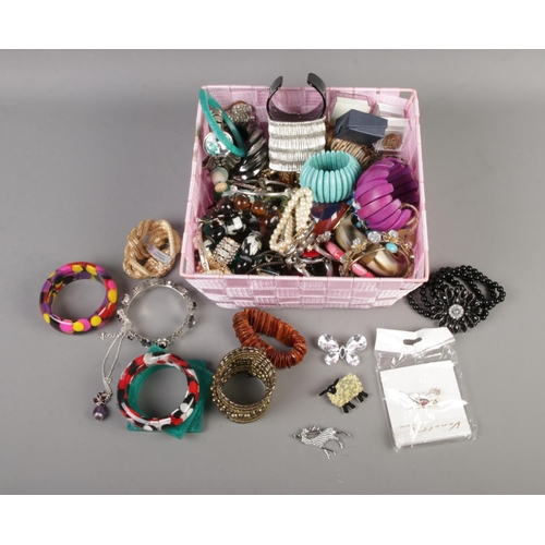 62 - A box of assorted costume jewellery to include bangles, brooches, pin badges, etc.