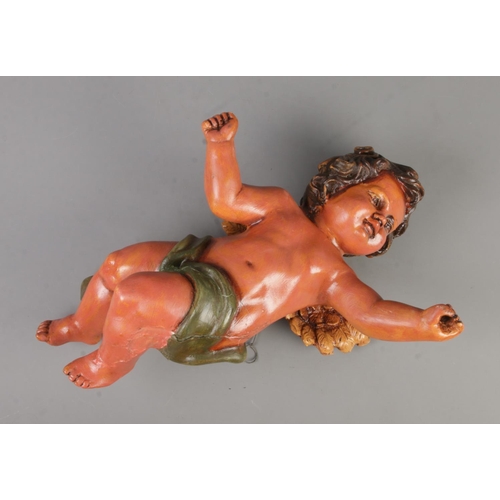 303 - A large painted plaster wall hanging model of a cherub. Approx. length 53cm.