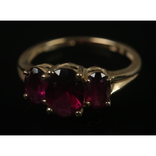 317 - A 9ct gold three stone ruby ring. Size L, 2.18g.