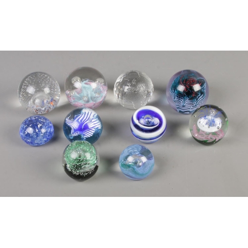 80 - A collection of ten glass paperweights to include Milliennium globe, Caithness and Selkirk glass exa... 