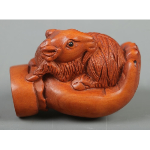 399 - A Japanese carved Netsuke in the form of a goat on hand