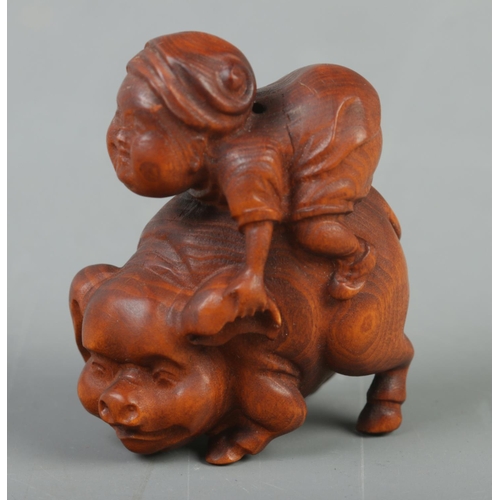 403 - A Japanese carved Netsuke in the form of a boy riding a pig