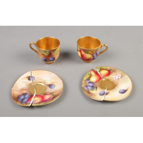 437 - A pair of Royal Worcester hand painted gilt china cups and saucers decorated with fruit.