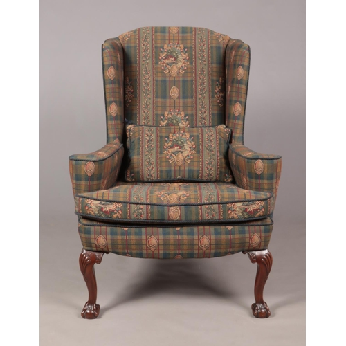 135 - An antique style wing back arm chair raised on carved mahogany ball and claw feet, along with a foot... 