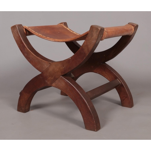 139 - Robert 'Mouseman' Thompson, an oak xframe stool with leather seat. Having carved mouse signature.