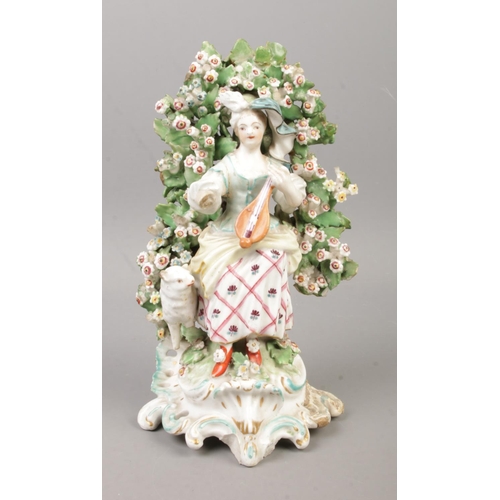22 - An 18th century Derby porcelain figure modelled as a loot player with bocage surround. 20cm.