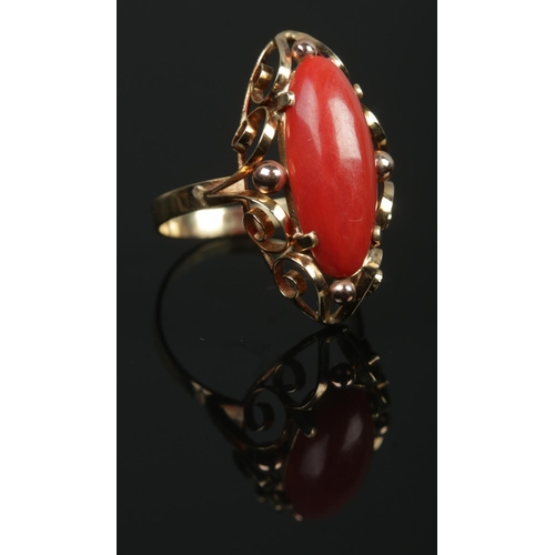 92 - A 14ct gold cabochon coral ring with scrollwork border. Coral length approximately 2cm. Size Q. 3.97... 