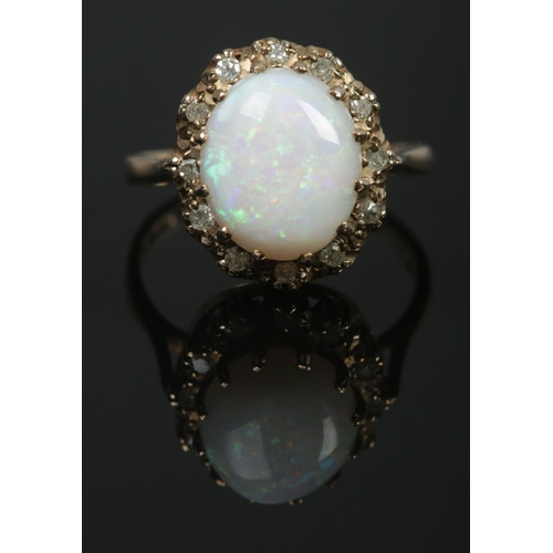 96 - A 9ct gold dress ring set with a large cabochon opal stone within a diamond halo surround. Hallmarks... 