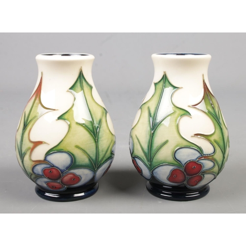 107 - A pair of small Moorcroft pottery vases decorated in the Holly  pattern by Philip Gibson. Date cyphe... 