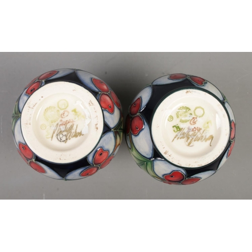 107 - A pair of small Moorcroft pottery vases decorated in the Holly  pattern by Philip Gibson. Date cyphe... 