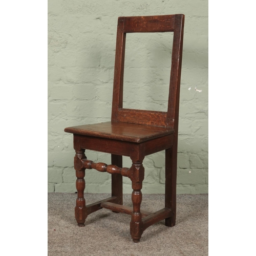 567 - A late eighteenth/early nineteenth century oak hall chair, with turned support and central stretcher... 