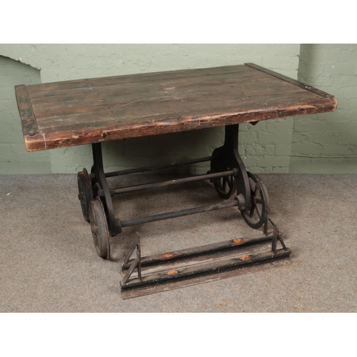 583 - A slated pitch pine table, raised on cast iron slate wagon base. Featuring six-spoke wheels and matc... 