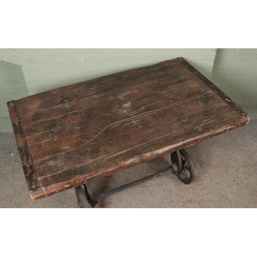 583 - A slated pitch pine table, raised on cast iron slate wagon base. Featuring six-spoke wheels and matc... 