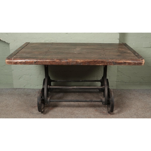 583 - A slated pitch pine table, raised on cast iron slate wagon base. Featuring six-spoke wheels and matc... 