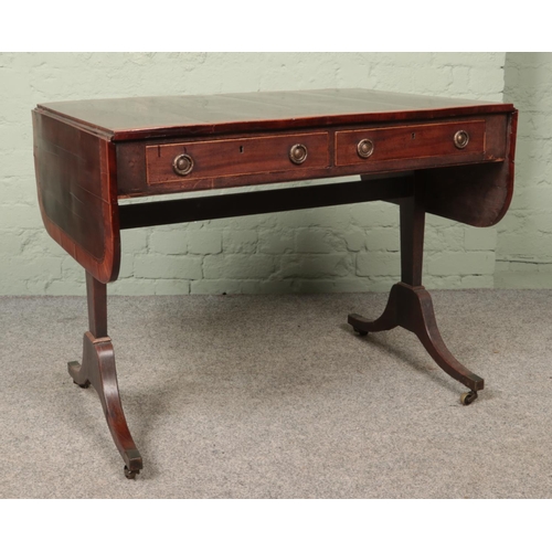 594 - A regency style mahogany sofa table with two drop hoop handle drawers and brass castors.

Hx71cm
Wx1... 