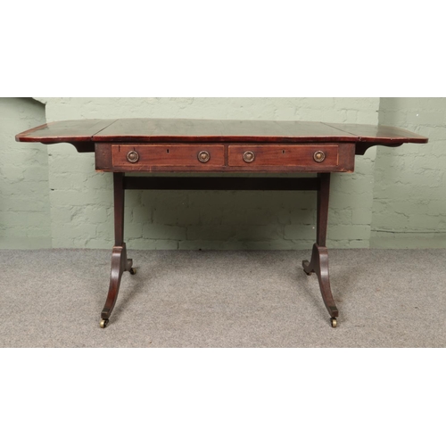 594 - A regency style mahogany sofa table with two drop hoop handle drawers and brass castors.

Hx71cm
Wx1... 