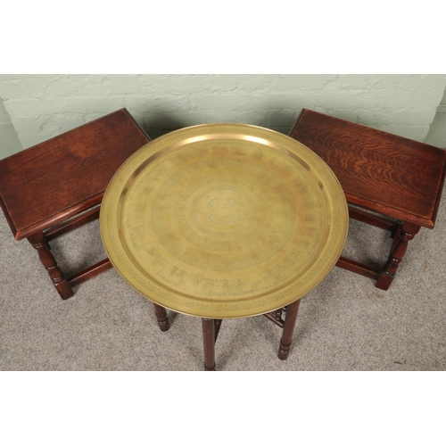 596 - A middle Eastern brass circular topped table with wooden folding base along with two oak side tables... 