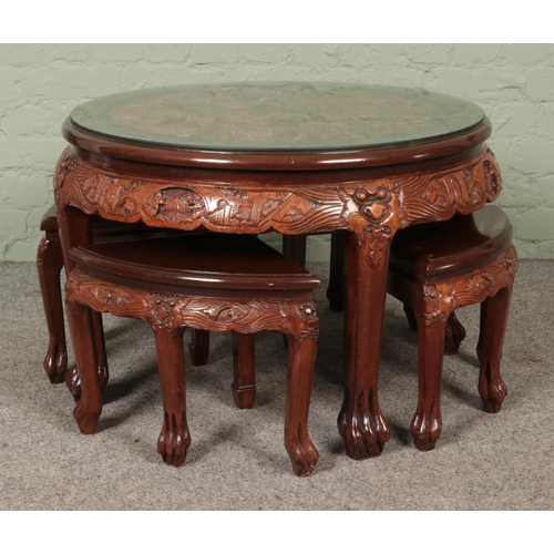 597 - Mahogany coloured carved Chinese design circular glass top coffee table with four smaller tables nes... 