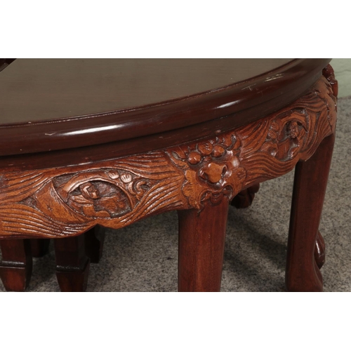 597 - Mahogany coloured carved Chinese design circular glass top coffee table with four smaller tables nes... 