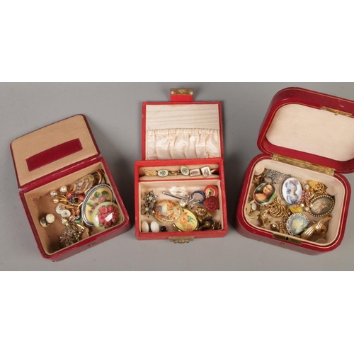 86 - Three red leather jewellery boxes and contents. Includes studs, cufflinks, clip on earrings, brooche... 