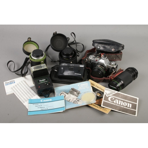 90 - A camera bag with contents of Canon AV-1 camera, Olympus Trip 100, lenses, flash unit etc.