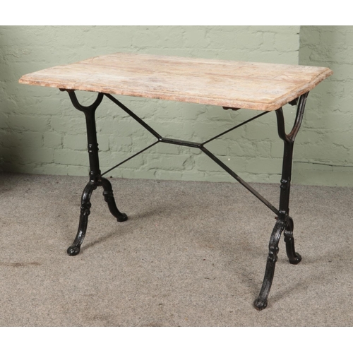 554 - A cast iron pub table, with stained pine top. Height: 70cmm, Width: 91cm, Depth: 62cm.