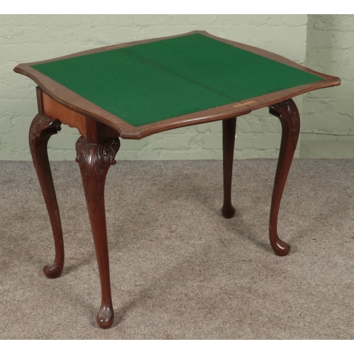 562 - A mahogany carved fold over card table with cabriole legs. Manufacturers label 