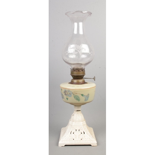 75 - A oil lamp with cast iron painted base and glass shade.