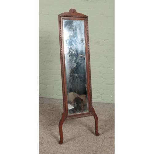 565 - An early 20th century carved oak cheval mirror with strut support. Height 140cm.