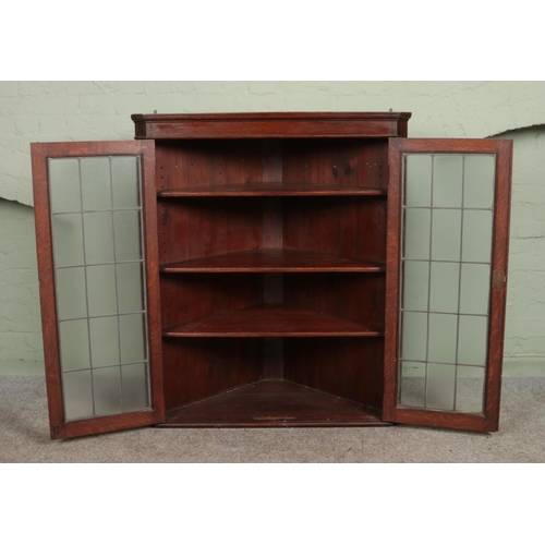 570 - A large Georgian style oak wall mounted corner cupboard, with twin lead glazed doors. Height: 127cm,... 