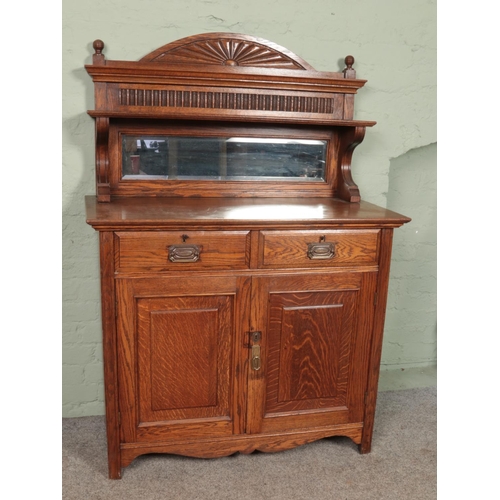 585 - A carved oak mirror back sideboard. Having drawer and cupboard base.