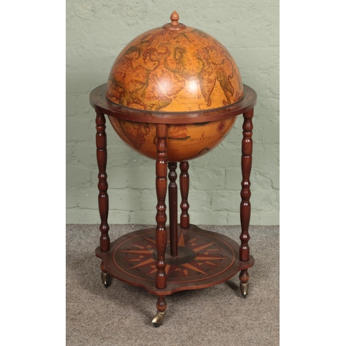 602 - A Globe drinks cabinet, with turned oak supports, hinged top, horoscopic border and rotating base. R... 